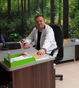 Czesław Osuch - chirurg ogólny, proktolog Dr n. med. Czesław Osuch, lekarz chirurg, w gabinecie medycznym, uśmiechnięty.